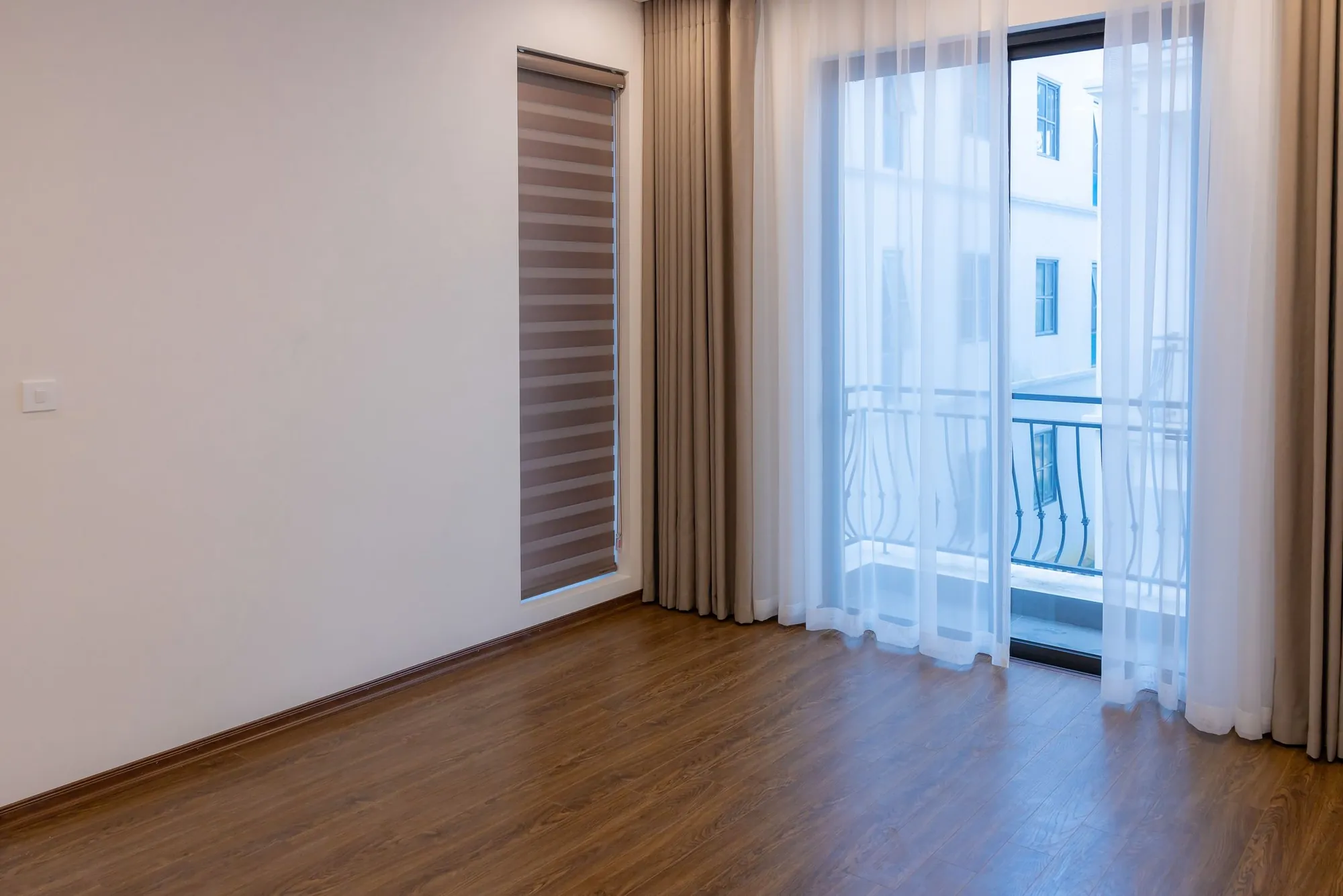 Sala com persiana rolô sobre piso de madeira