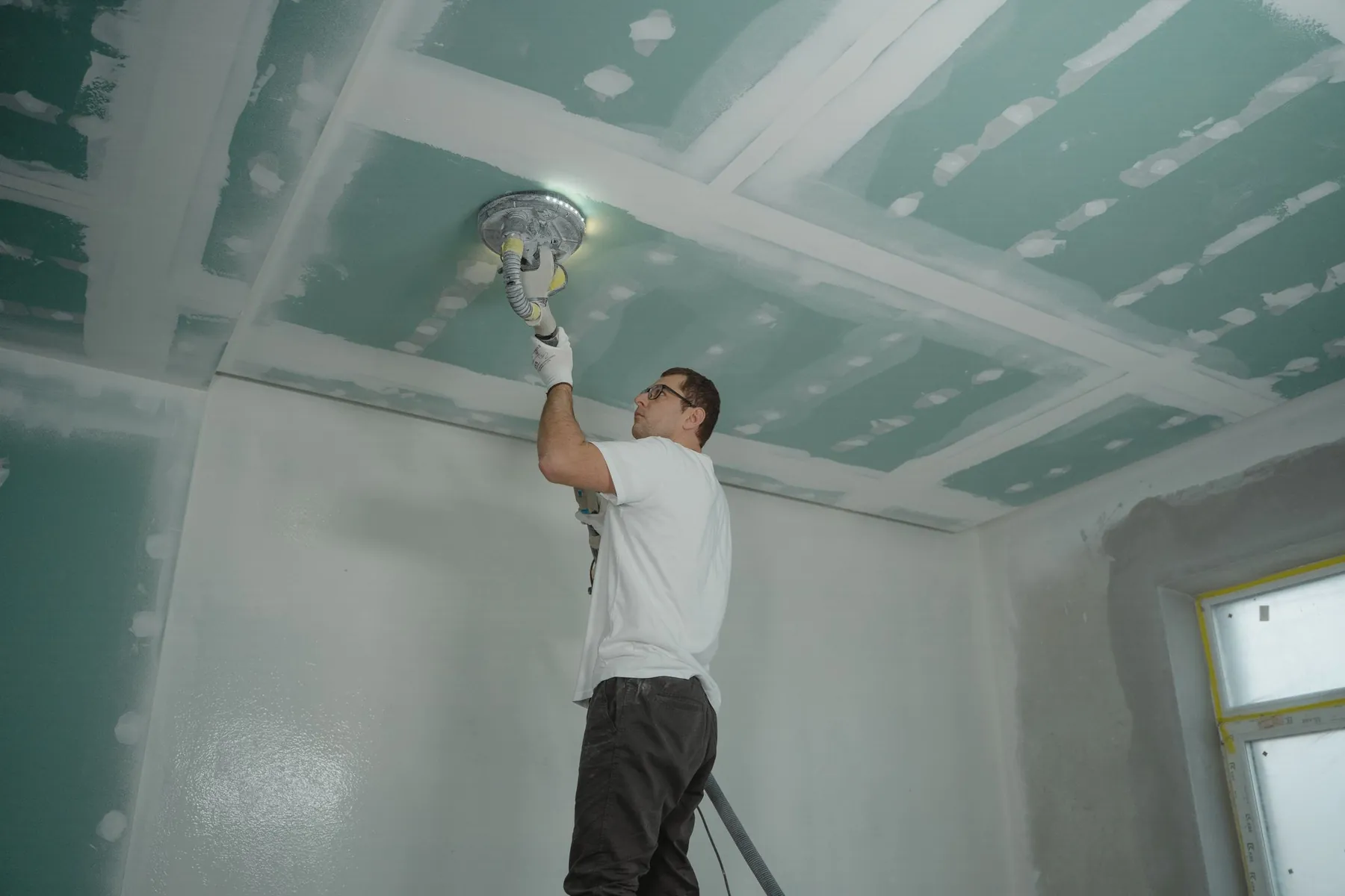 Profissional finalizando teto de drywall